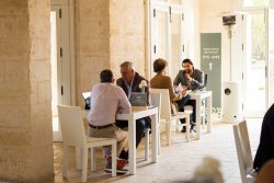 Delegates seated at table during personal meeting at Borgo Egnazia, laptops open and namecards visible